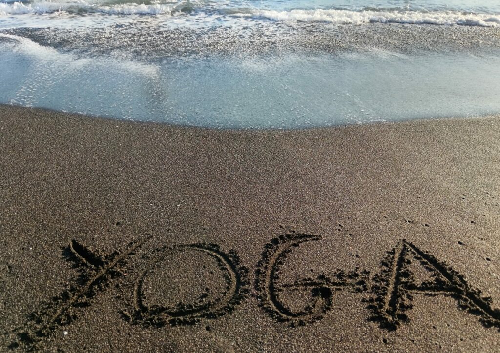 Le mot yoga écrit sur la sable, détente, vacances, expérience